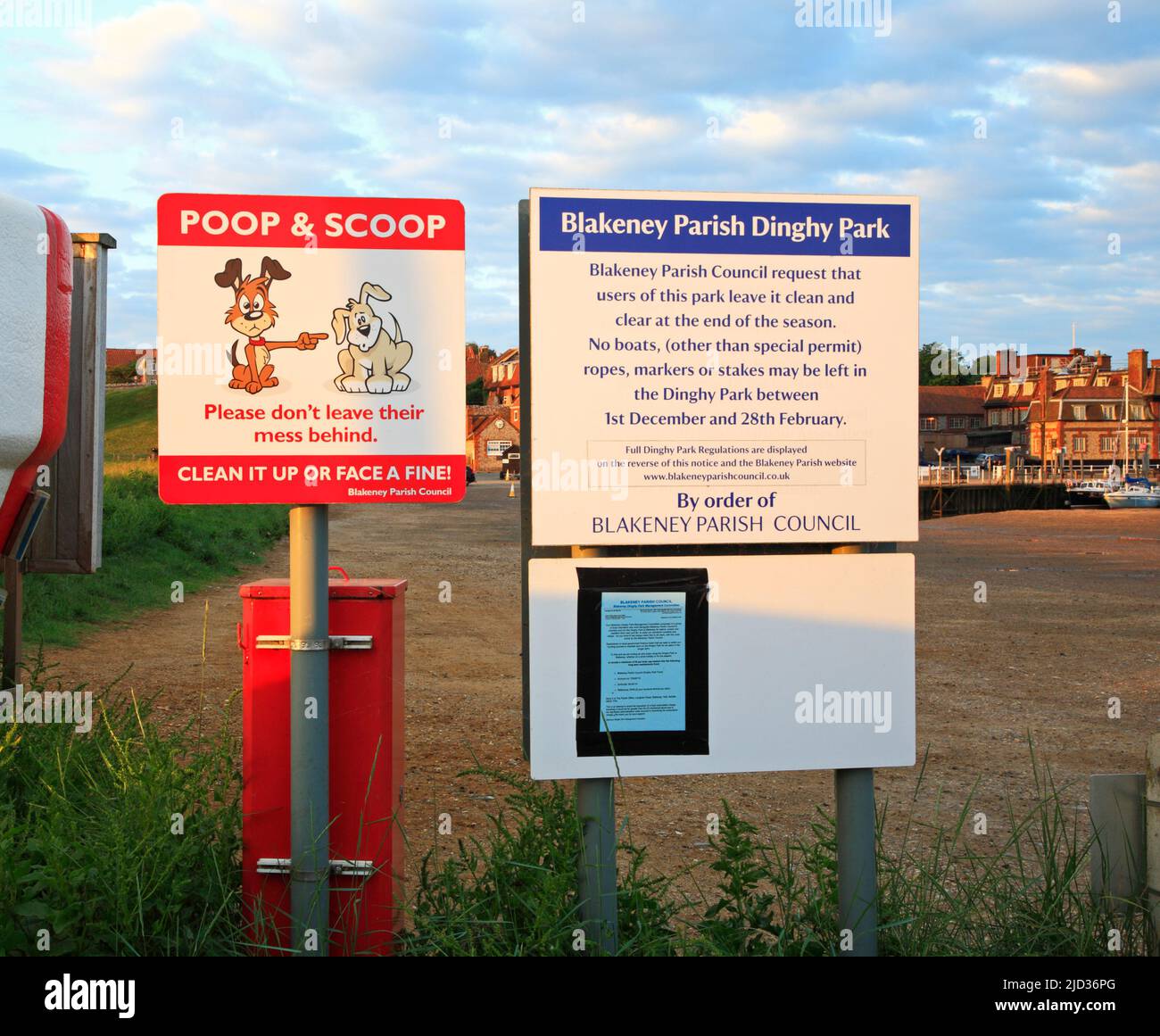 A Dinghy Park notice and a Poop and Scoop notice by the parking area by the quay in the village of Blakeney, Norfolk, England, United Kingdom. Stock Photo