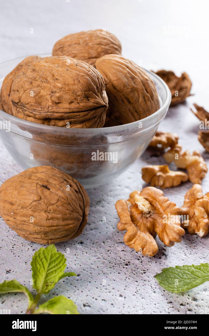Selective focus on walnuts in a bowl and kernels on white background Stock Photo