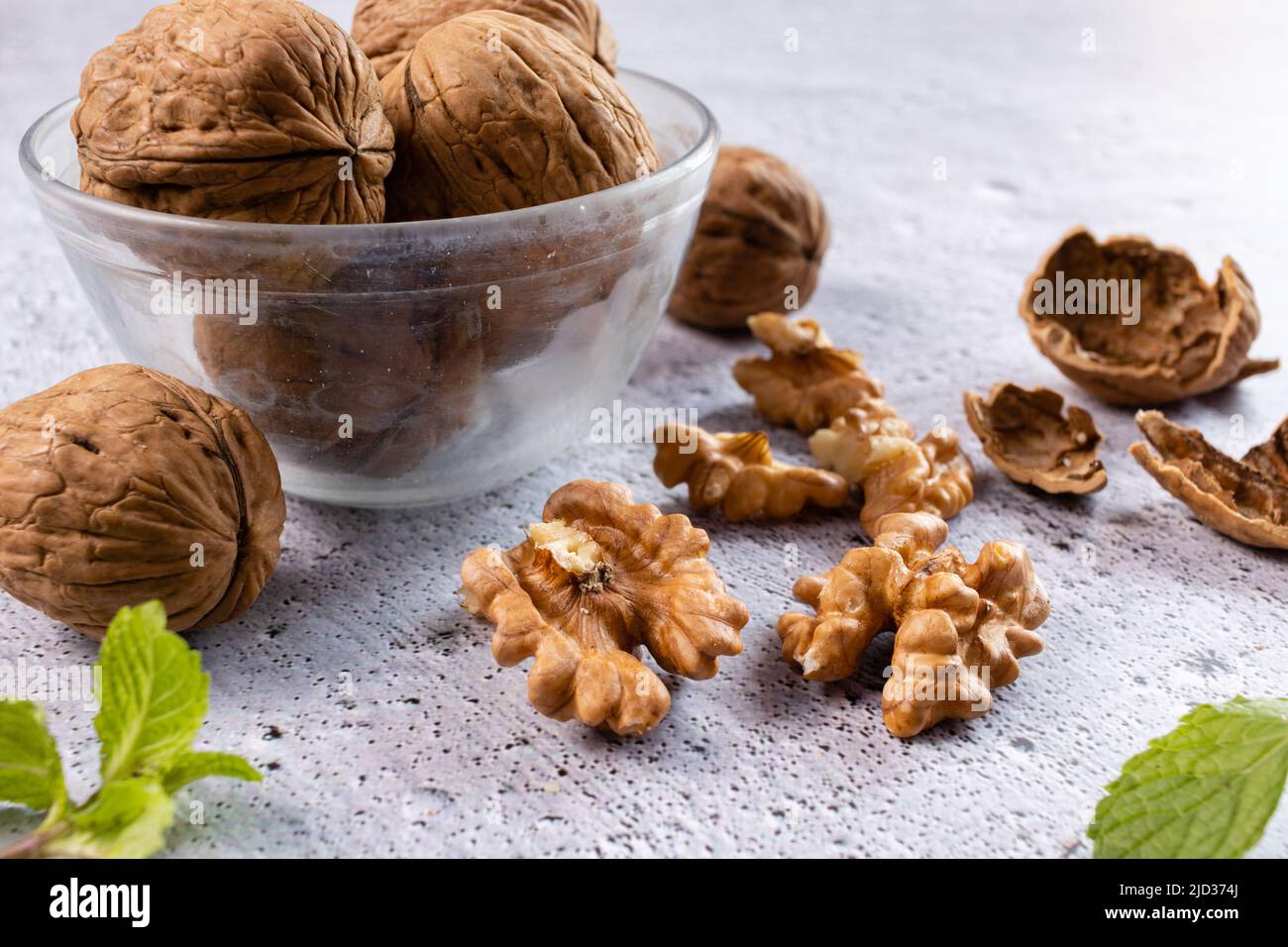 Selective focus on walnuts in a bowl and kernels on white background Stock Photo