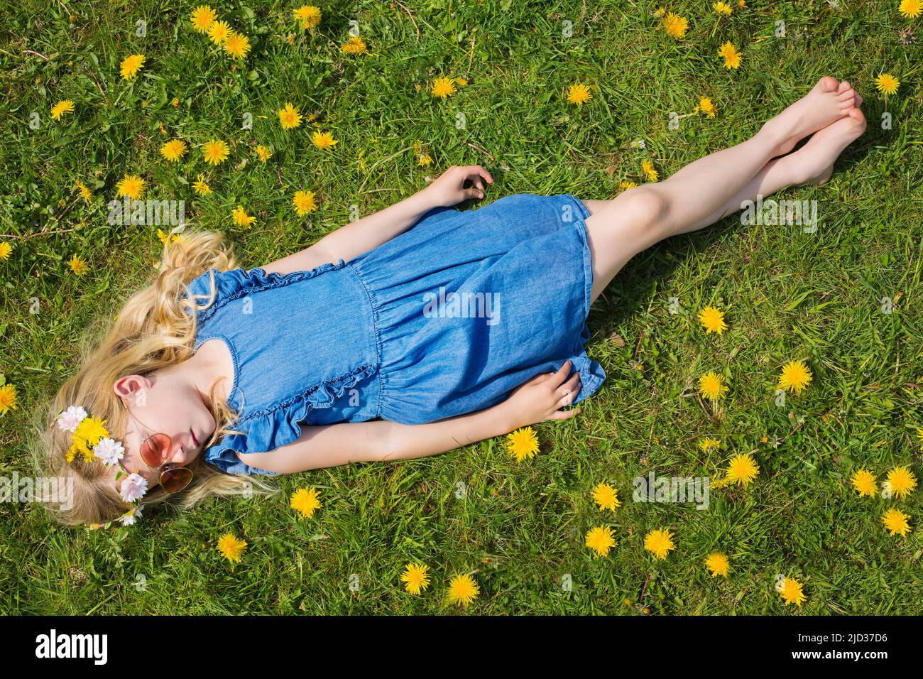 A little girl lying in a field of dandelions Stock Photo