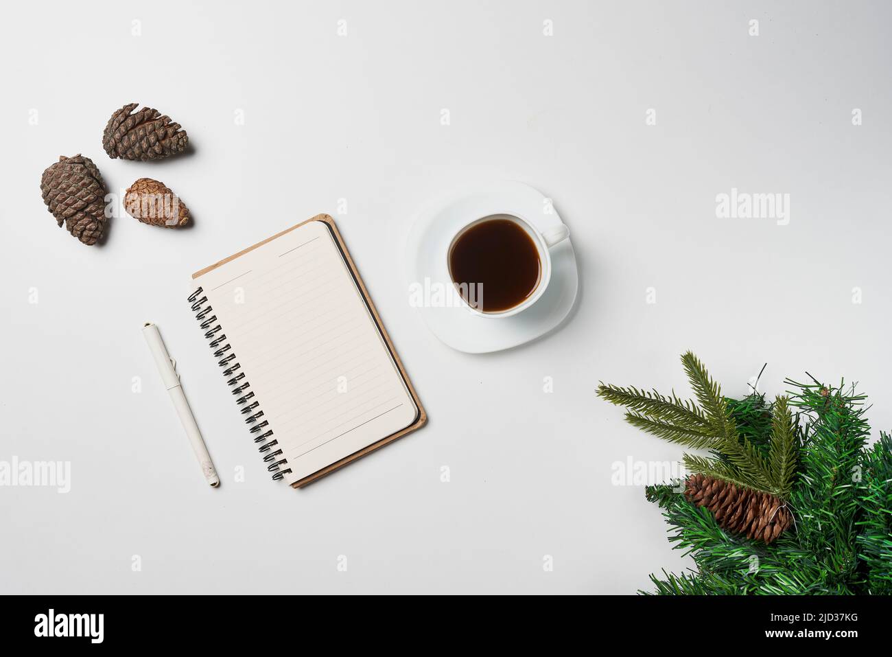 Christmas home office desk with notebook, cup of coffee and christmas decorations on white backgraund. Christmas card background notebook template. Top view with space for text. Stock Photo