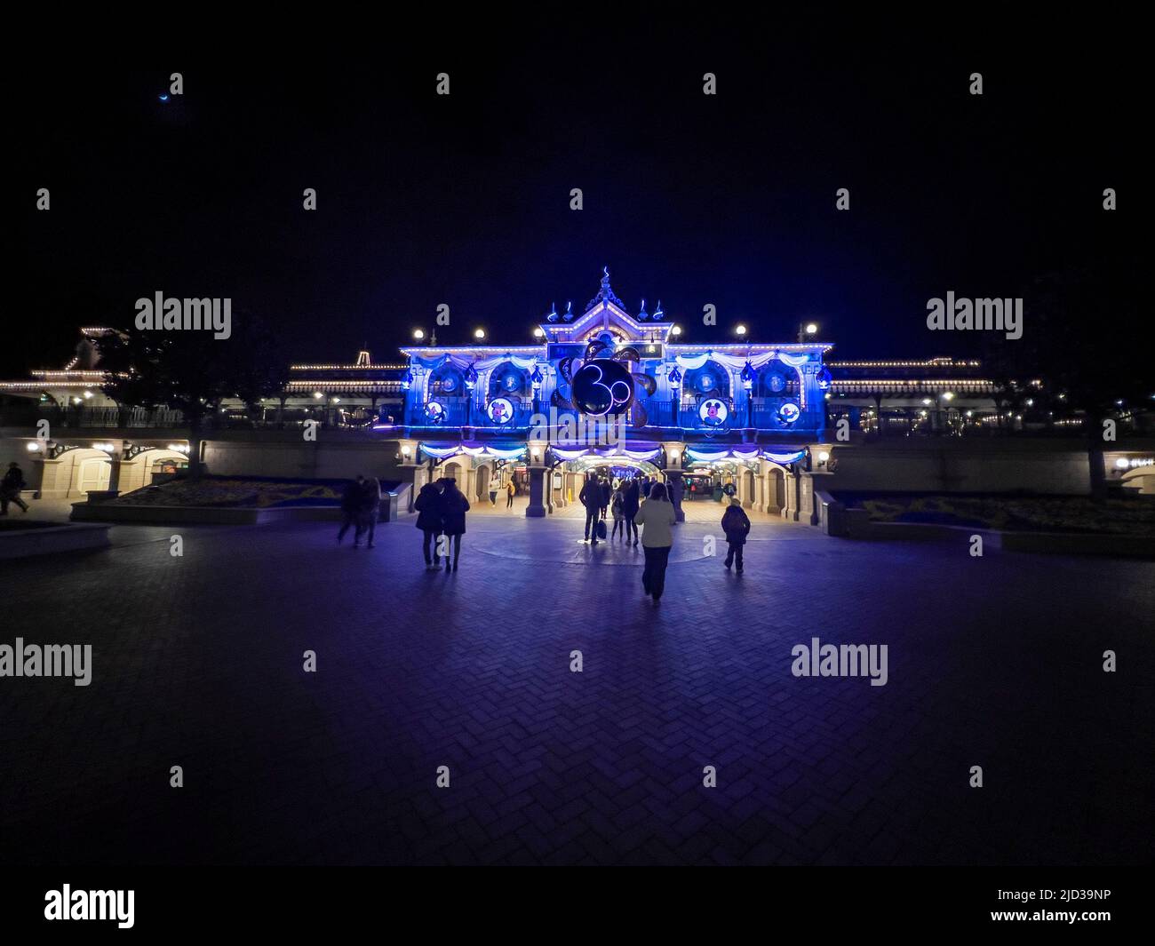 Paris, France - 04/05/2022: Colorful square of Disneyland by night. People walking around. Stock Photo