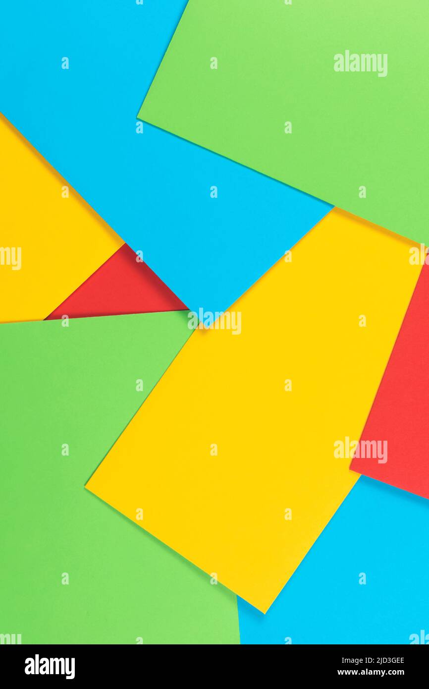 Geometric background made of randomly laid out colourful paper cards. Top view. Yellow, blue, red and green colours. Place for text. Stock Photo