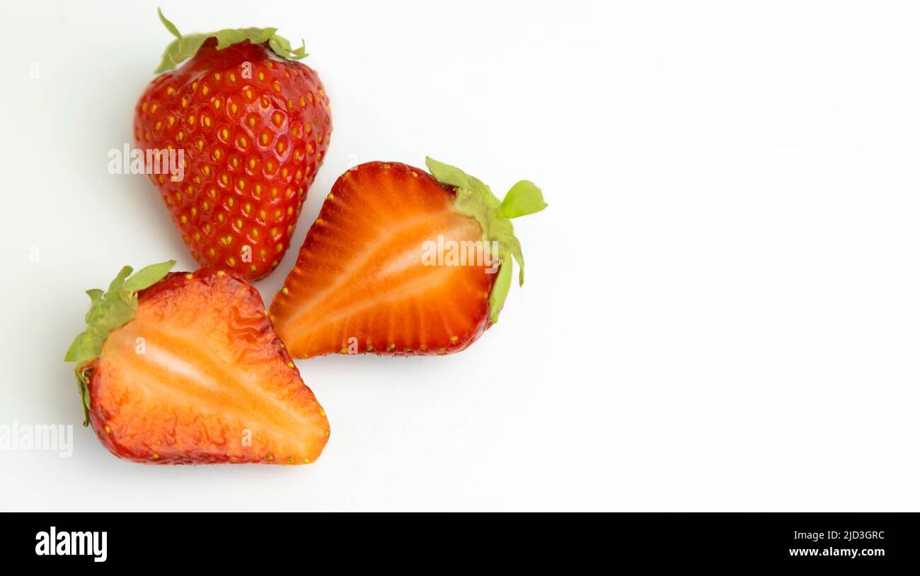 Juicy strawberries and two halves. Strawberries isolated on a white background. Place for text. Stock Photo