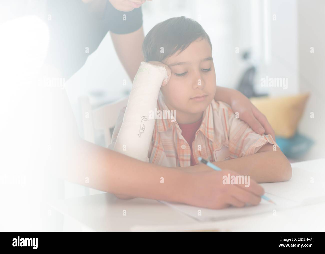 Boy with broken arm in gypsum having help from older brother for homework. High quality photo Stock Photo