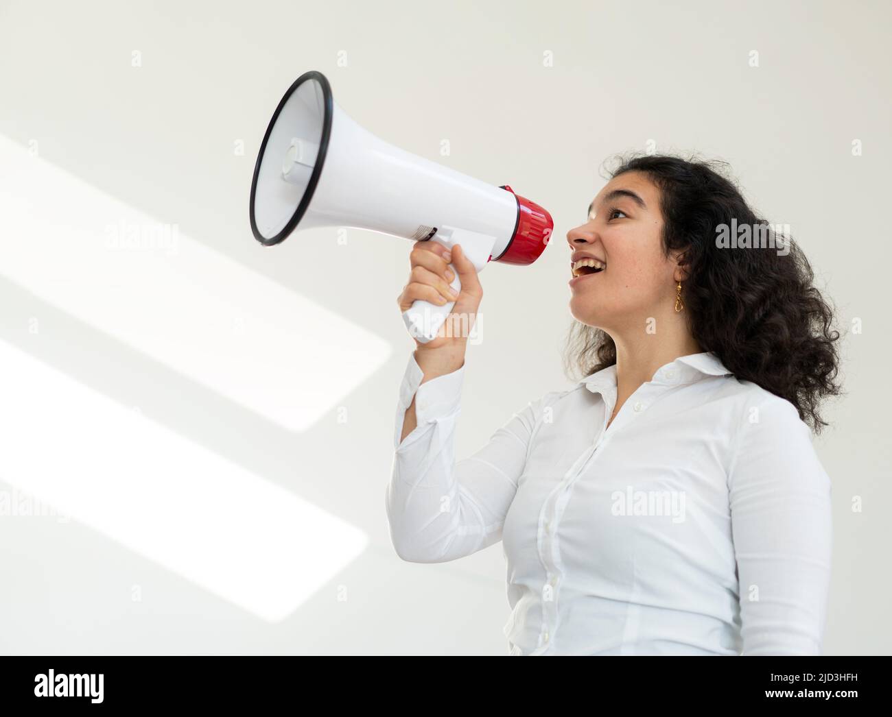 Beautiful business woman with curly hair holding a megaphone. High quality photo Stock Photo