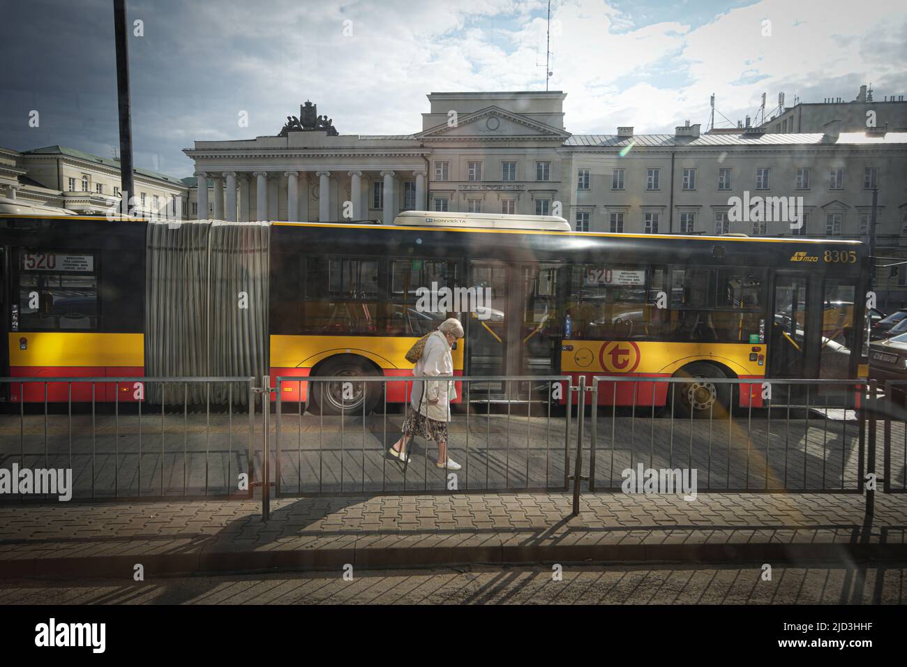 An elderly woman with a crutch is seen walking past a bus stop in Warsaw, Poland on 14 June