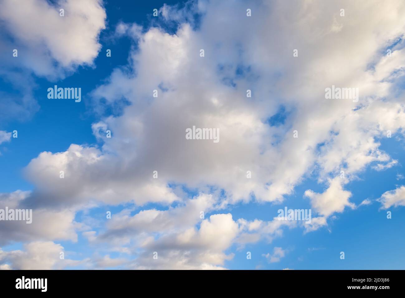 Fluffy clouds against the bright blue sky. Nature background. Stock Photo