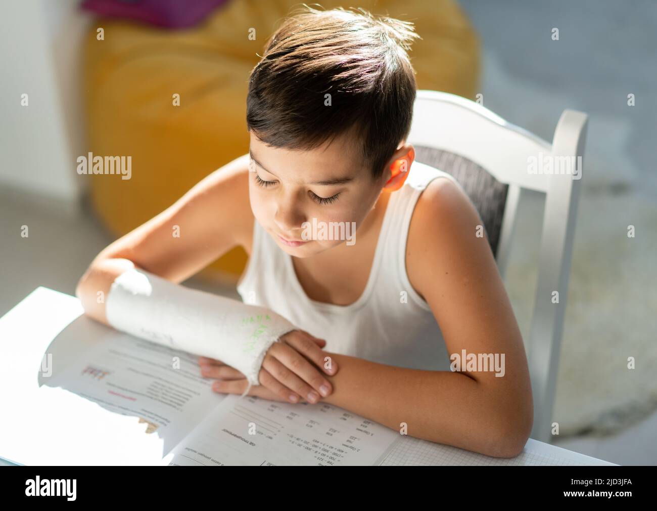 Back to school. Thinking child boy writing, drawing in notebook sitting at desk and doing homework. High quality photo Stock Photo