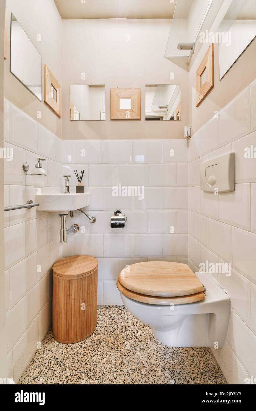 Wall hung toilet and small sink in corner in lavatory room with beige