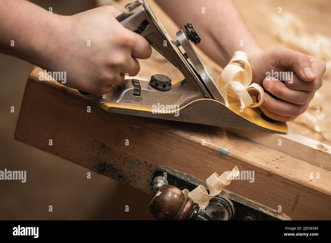 Closeup of unrecognizable, cropped joiner hand work with plane equipment tool on workbench