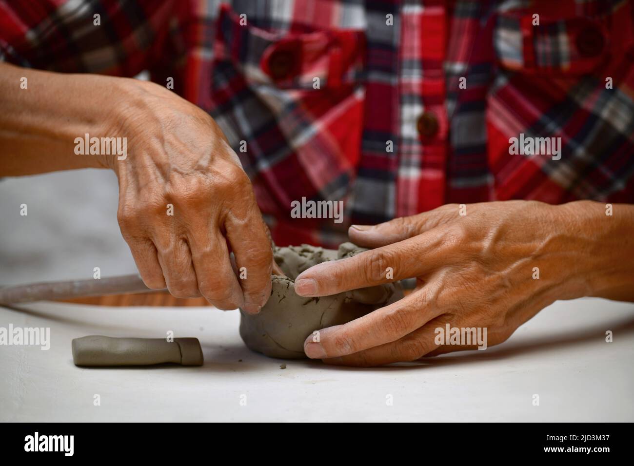 Close up view of an elderly woman molding a clay block  and making a ceramic pot Stock Photo