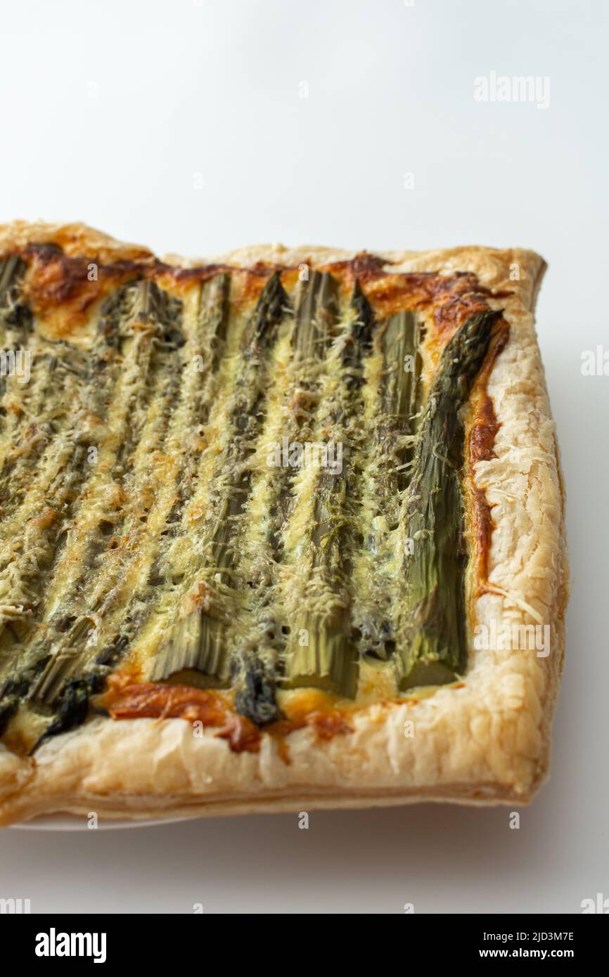 Baked puff pastry pie with cheese and asparagus on a white background, top view, copy space Stock Photo