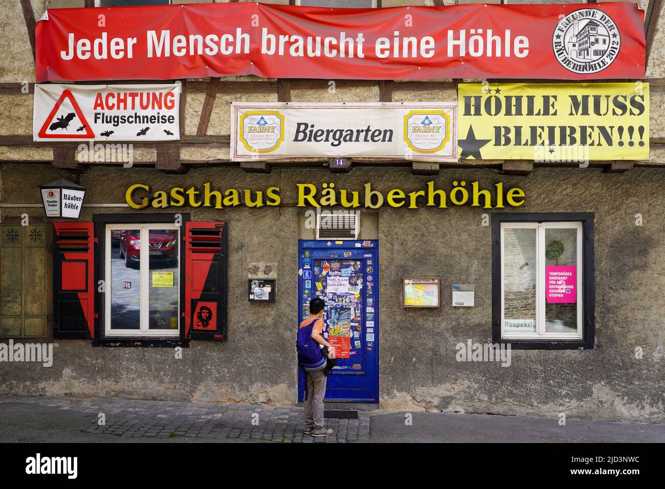 A man stands in front of the pub with beer garden, Räuberhöhle, Robber Cave, in Ravensburg, Baden-Württemberg, Germany, 6.6.22 Stock Photo