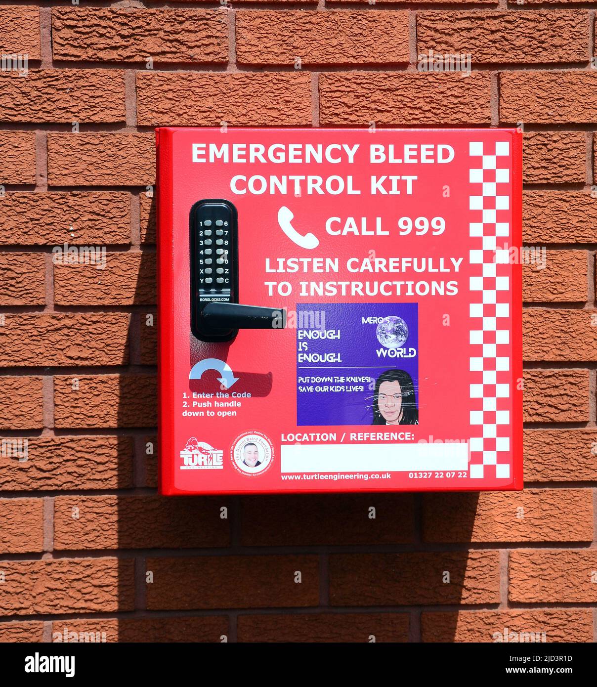 Emergency bleed control kit mounted in a red box on a brick wall with instructions on the front to call 999 emergency line in Manchester, England, UK. Stock Photo