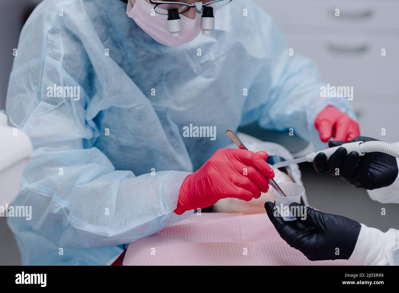 A female dentist with dental instruments prepares to apply the solution before brushing her teeth in the office of the dental clinic. High quality pho Stock Photo