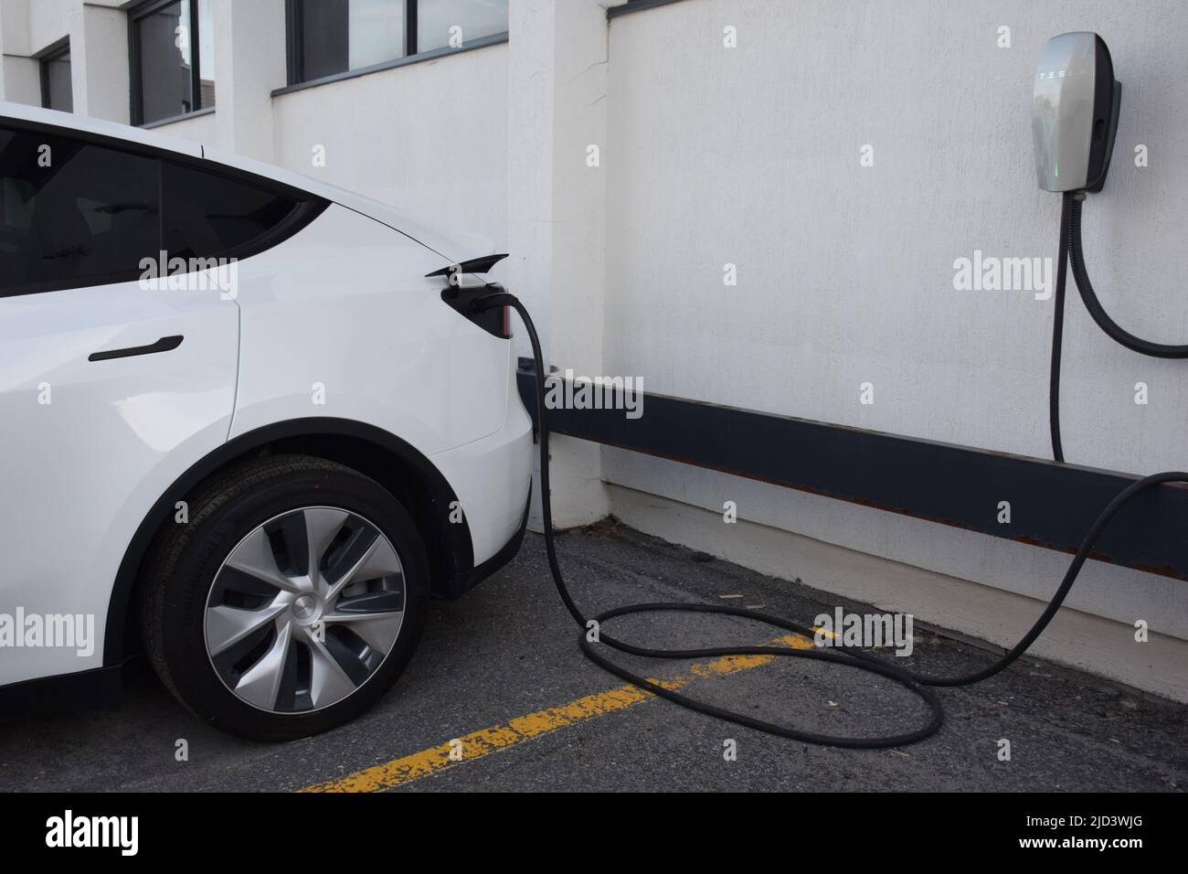 Close up of white electric car connected to charging cable Stock Photo
