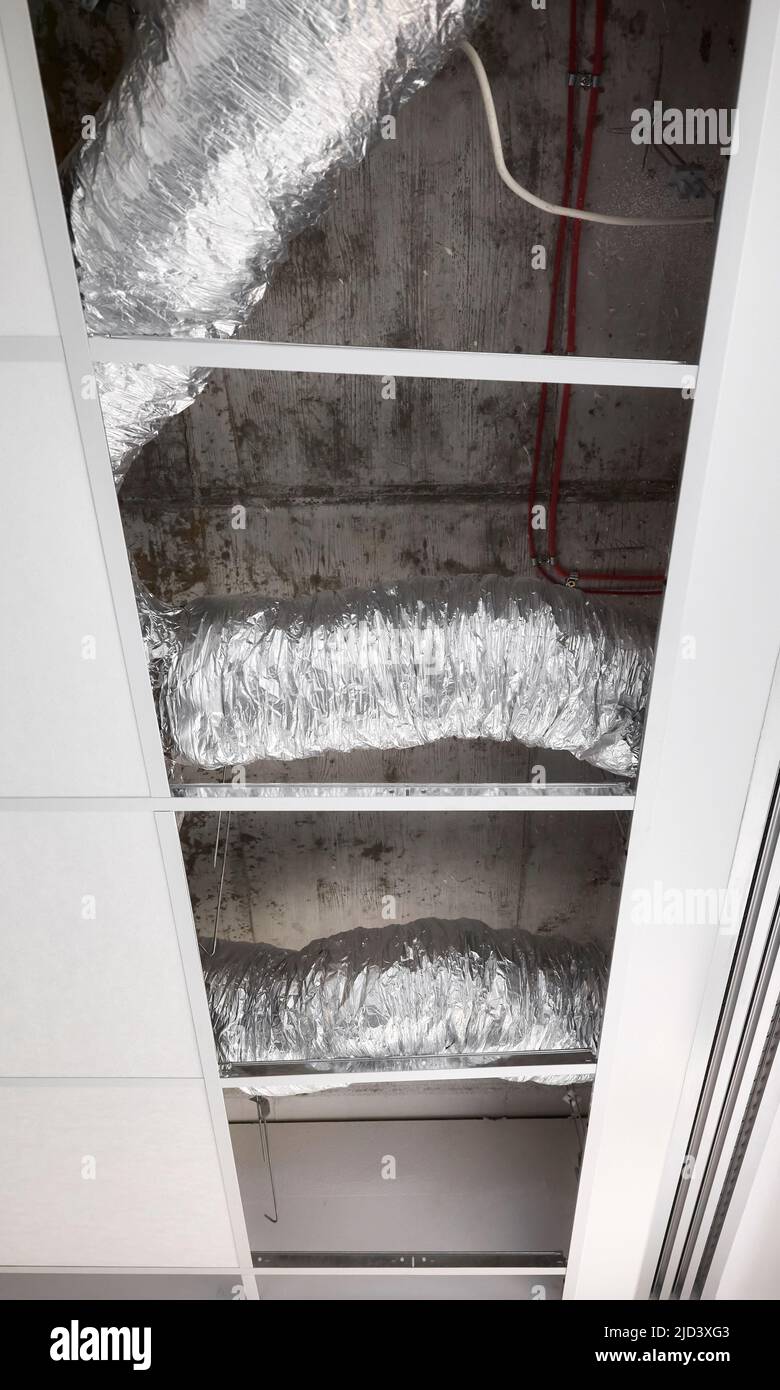 Ventilation pipes in silver insulation material in suspended ceiling during renovation. Stock Photo