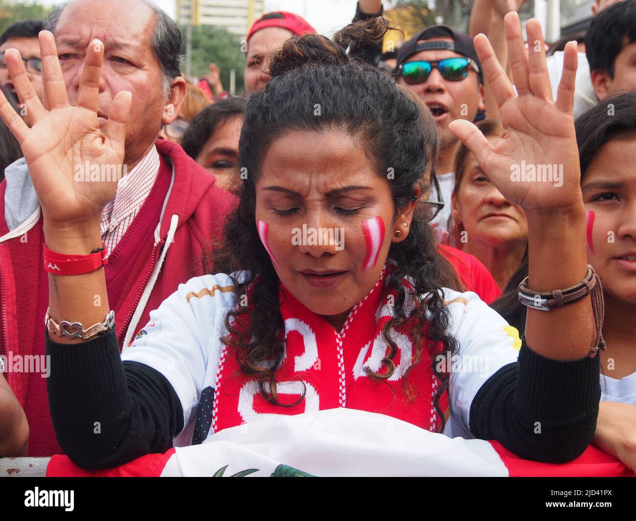 A woman praying with her arms raised above the Peruvian flag when