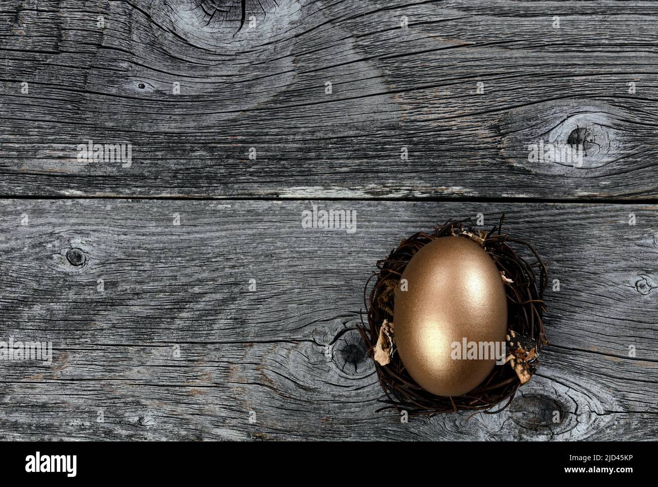 Golden egg in nest on rustic wood background for investment or retirement concept Stock Photo