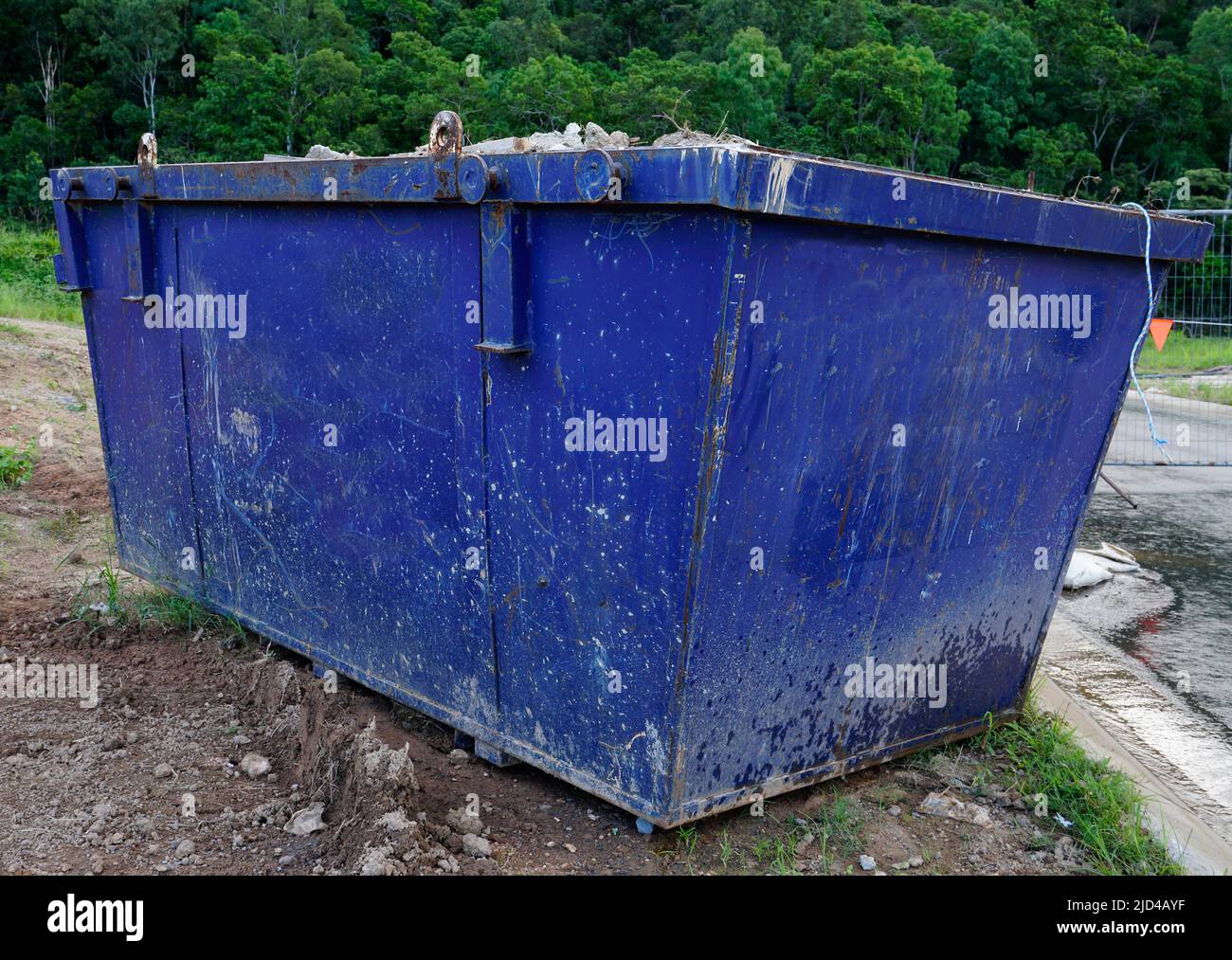 blue metal waste skip filled with household rubbish on building site Stock Photo
