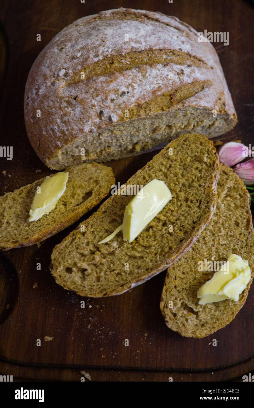 Sliced fresh bread with slices of butter and garlic cloves Stock Photo