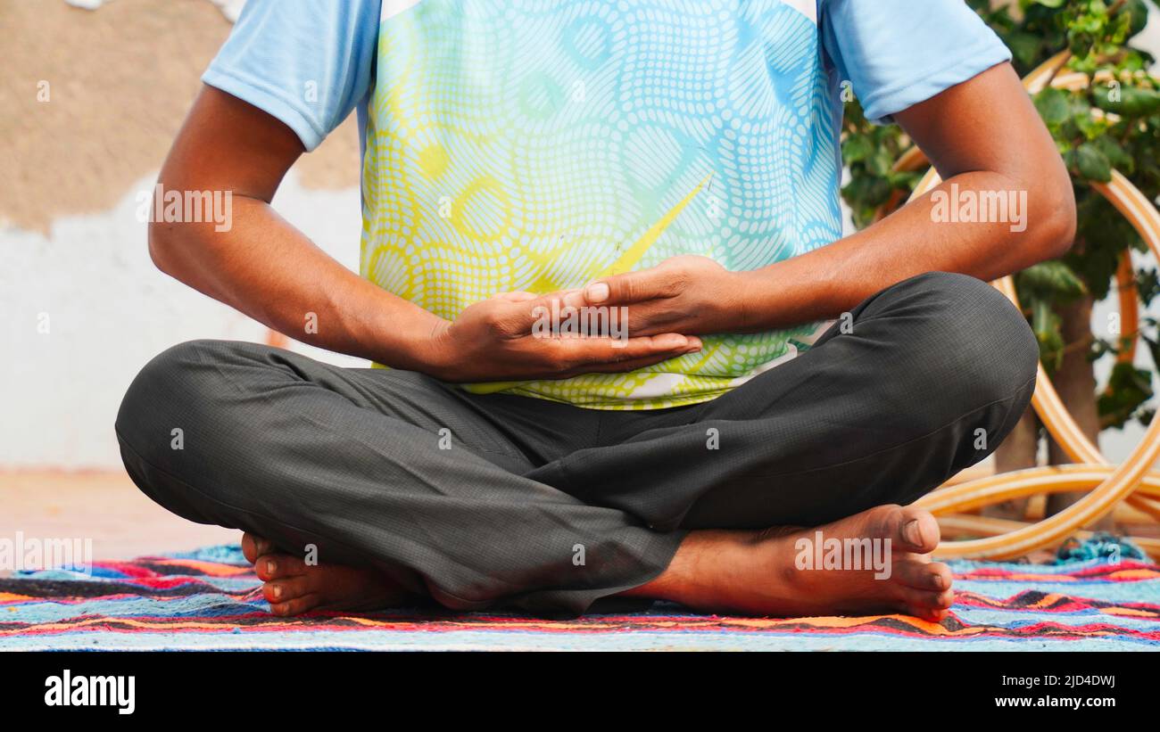 young Indian man sitting in lotus position on her yoga mat in ...
