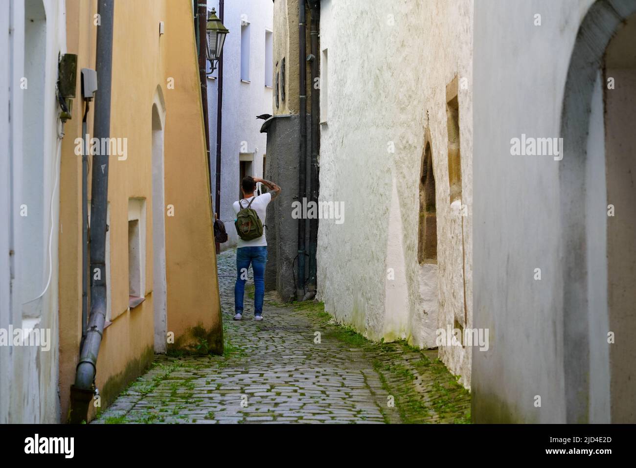 A tourist takes a photo in a small alley in the old town of Passau, Bavaria, Germany, 11.6.22 Stock Photo