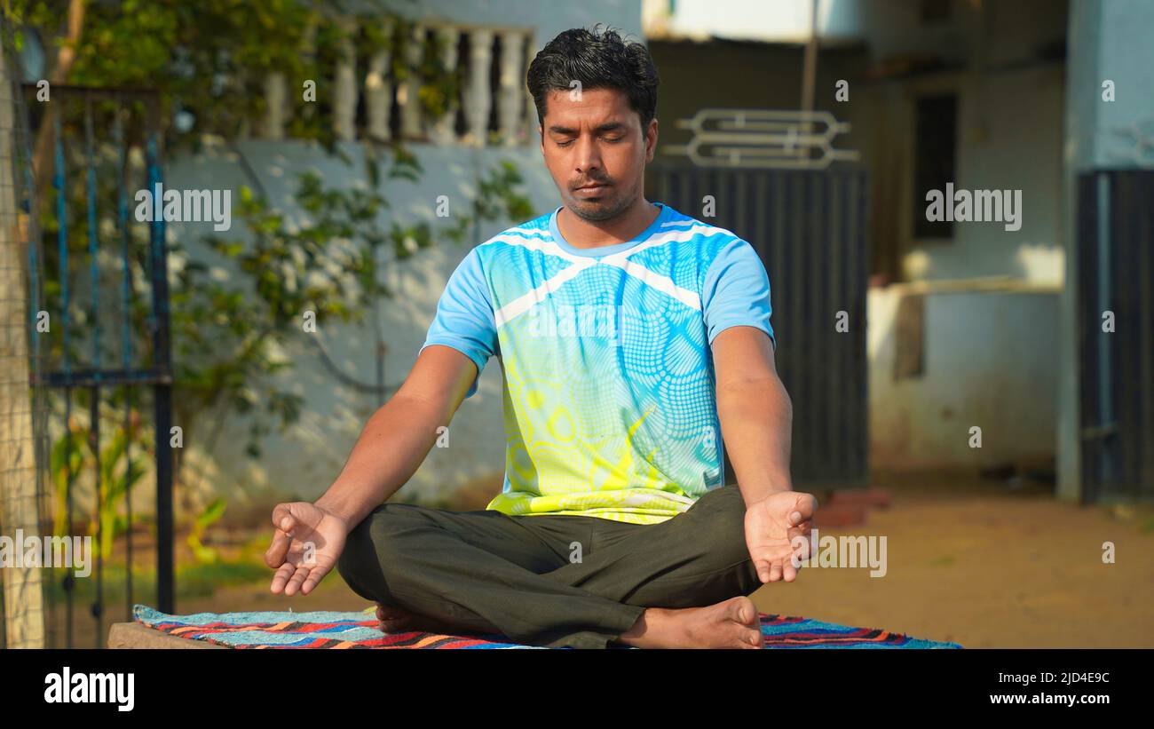 young Indian man sitting in lotus position on her yoga mat in ...