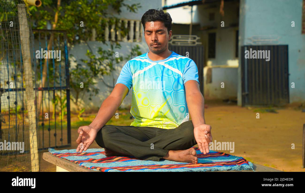 Relaxed young man doing yoga and meditating outdoors. Stock Photo