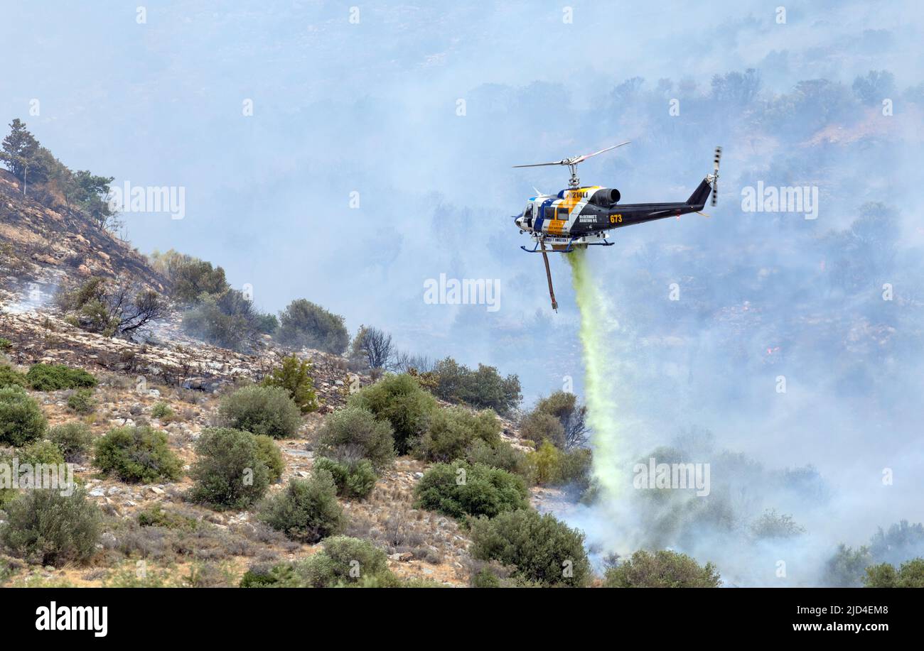 Athens, Greece, June 4, 2022: A firefighting McDermott Aviation Bell 214B helicopter operates in Hymettus mount wildfire near Glyfada suburb of Athens. Stock Photo