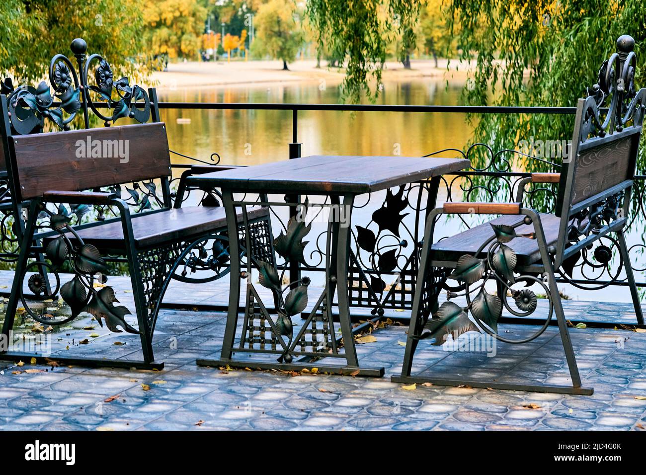 Benches and a table made of carved metal iron wood in a cafe on the shore  Stock Photo