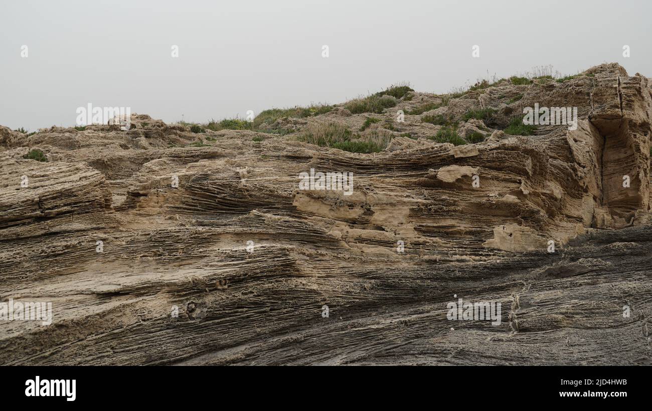 Volcanogenic rock slabs on the seashore. Natural rocky breakwater at ...