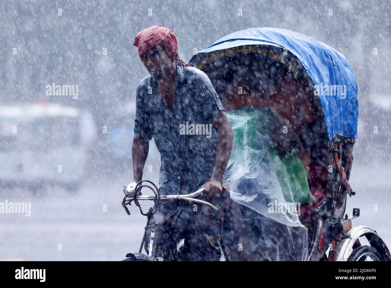 A man pulls a rickshaw during heavy rains that caused widespread flooding in the northeastern part of the country, in Dhaka, Bangladesh, June 18, 2022. REUTERS/Mohammad Ponir Hossain Stock Photo