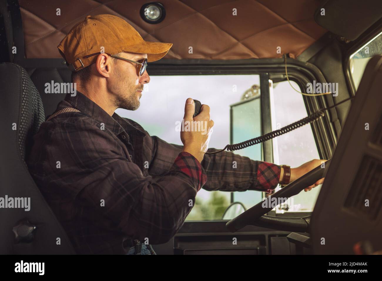Closeup of Professional Truck Driver Communicating Through His CB Radio While Completing a Cargo Delivery. Useful Trucker Tools. Stock Photo