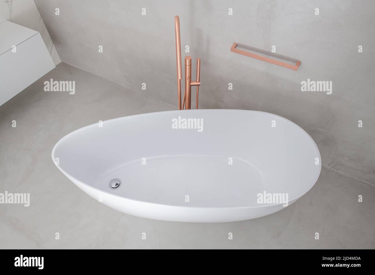 Minimalistic Freestanding White Bathtub with Golden Tub Filler in Freshly Renovated Modern Style Bathroom Finished in Light Grey and Beige Colors. Lux Stock Photo