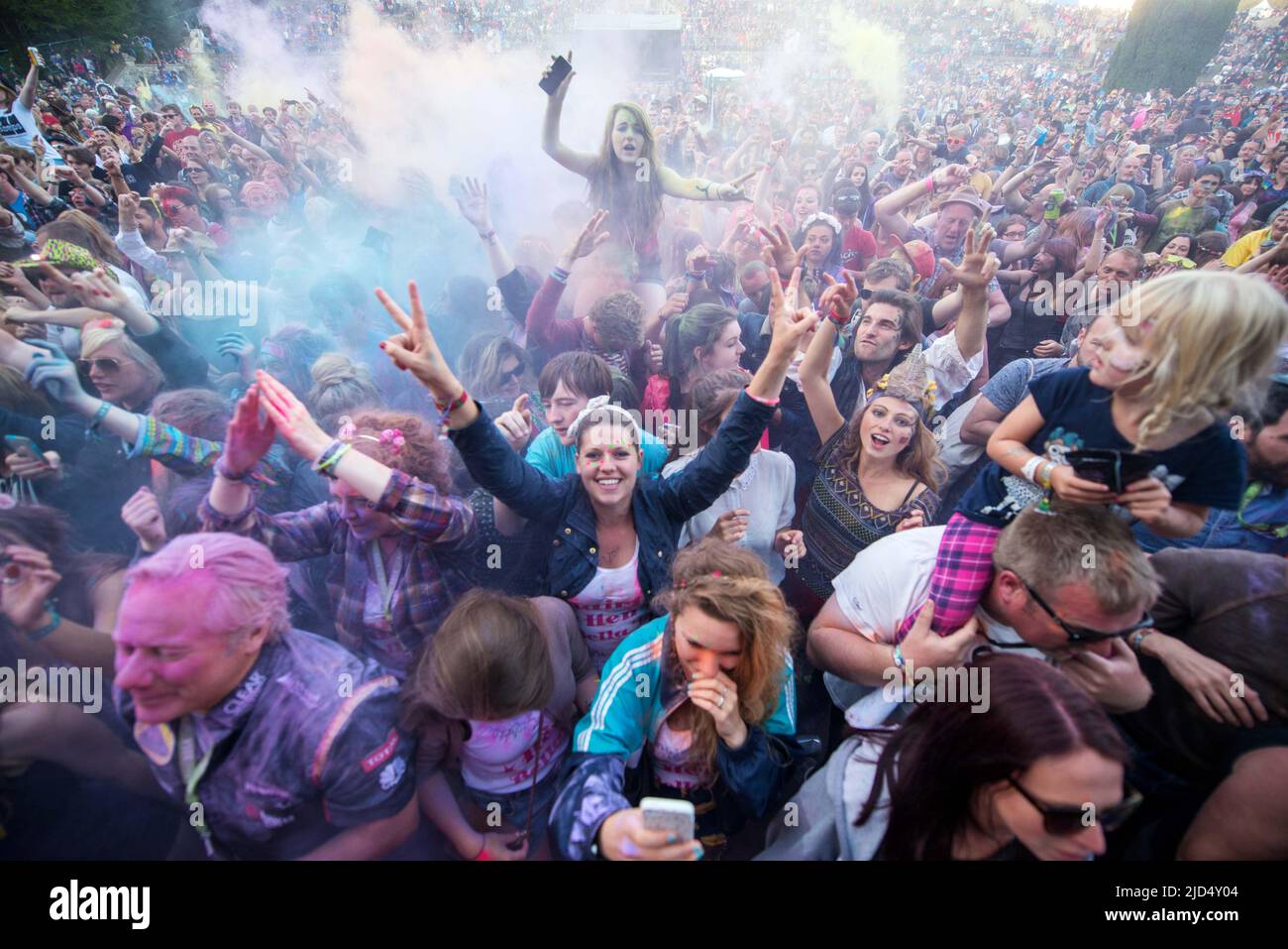 Festival goers throw colored powder at the main stage at Belladrum Tartan Hearts Festival at Inverness, United Kingdom Stock Photo