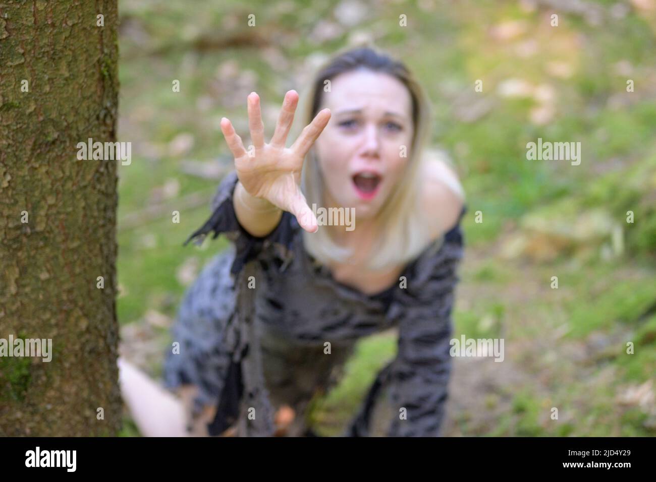 Anguished woman screaming and reaching up to the camera clawing with her hand and focus on hand Stock Photo