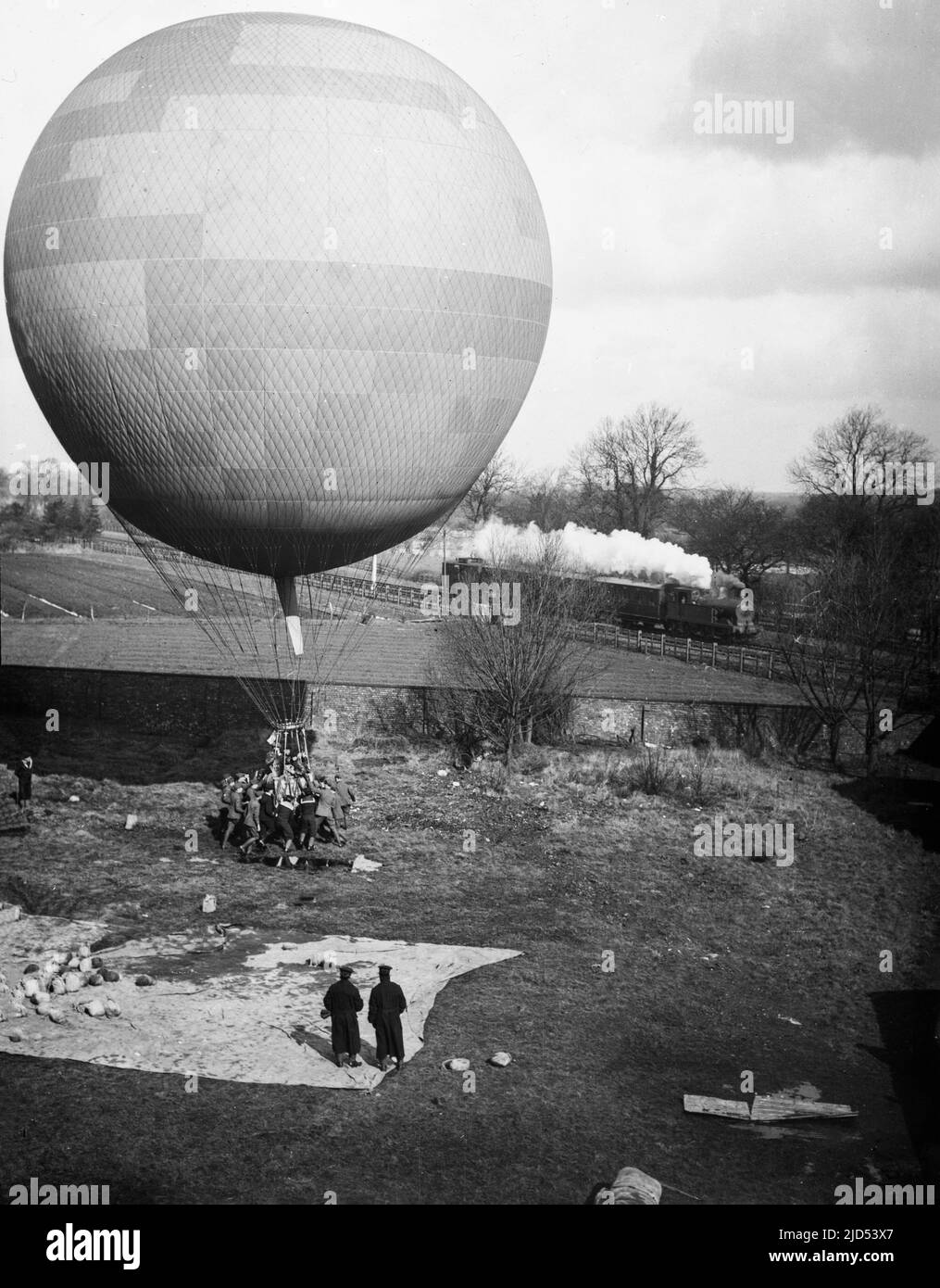 An early 20th century black and white photograph showing the launching of a British Coal Gas Powered observation balloon, with a Steam Locomotive passing by. Stock Photo