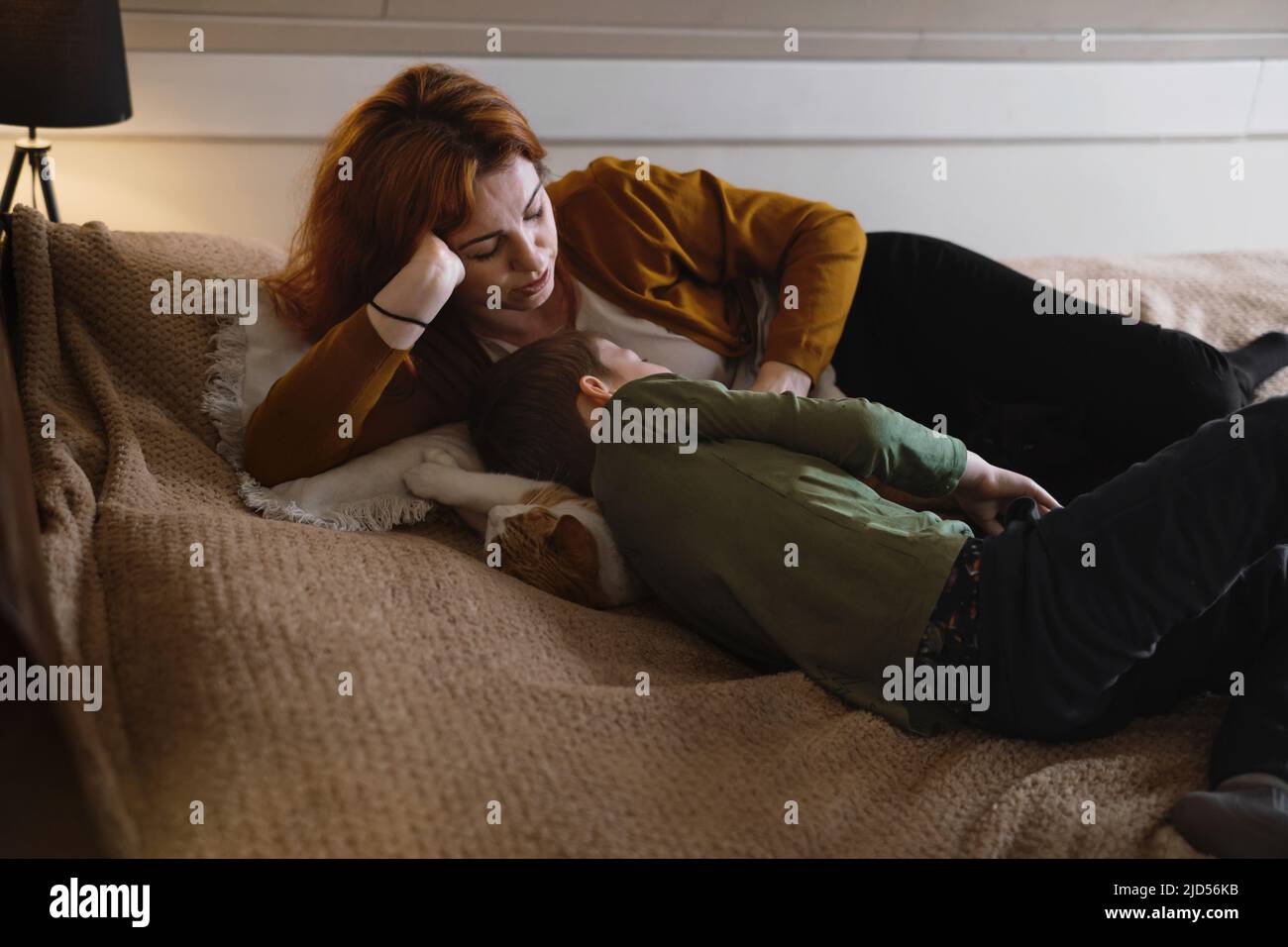 Middle age woman mother with son. Female hugging her lovely teen child in bedroom in the evening. Copy space. Adorable family concept. Stock Photo