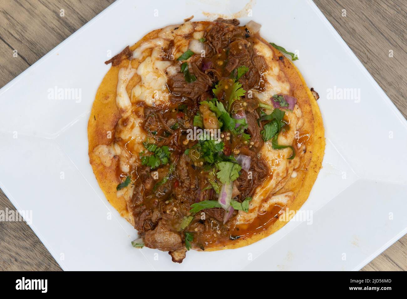 Overhead view of appetizing birria taco with all the toppings  for a tempting Mexican food delicacy. Stock Photo