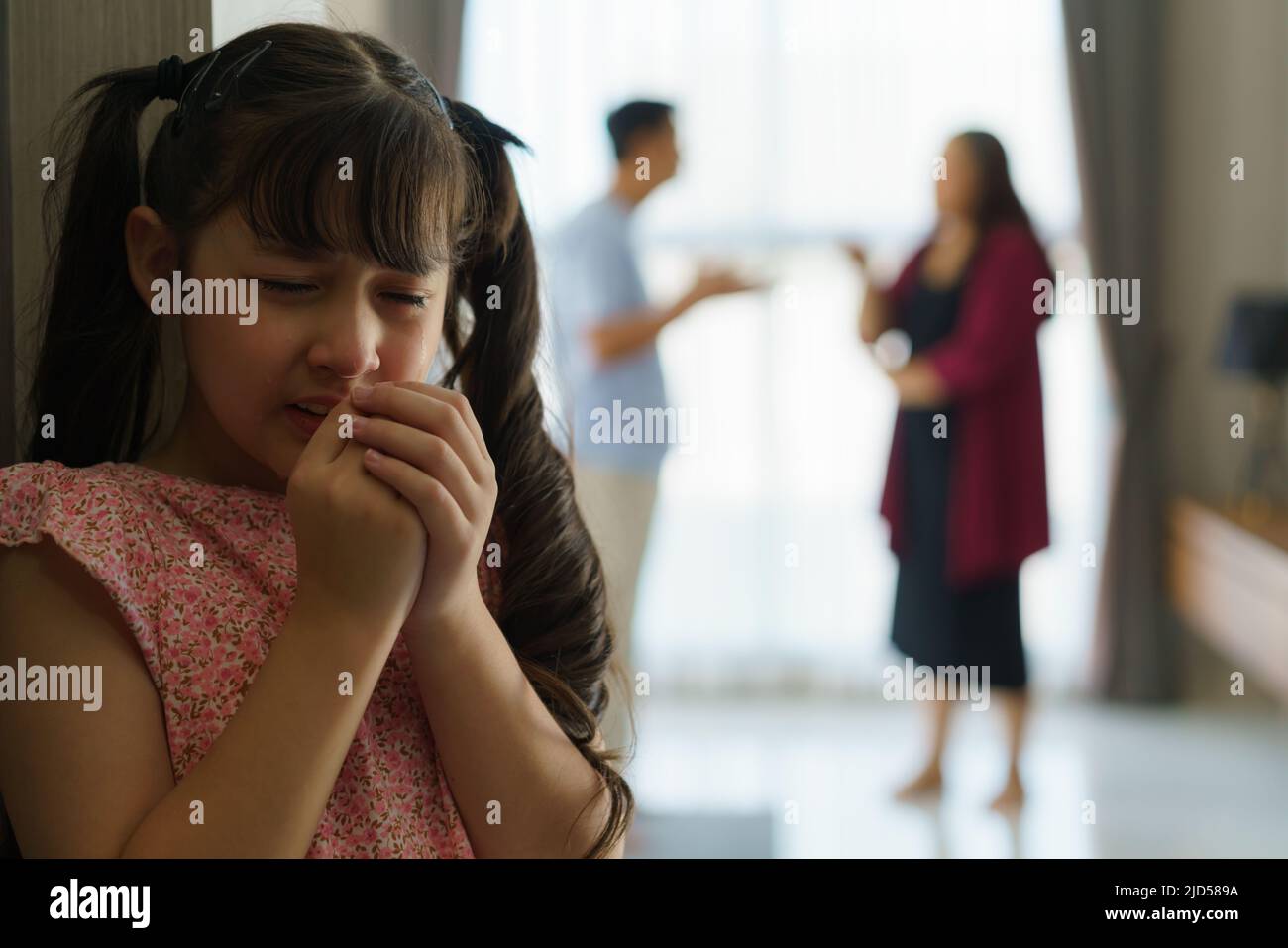 Family violence and family conflict concept, sad little girl with blur of mother fighting father with quarrel at home. Stock Photo