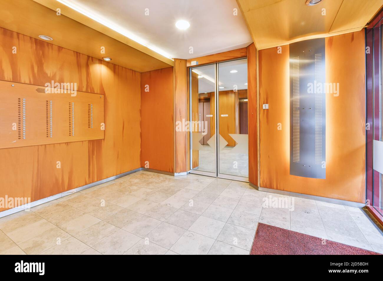 Shiny elevator with opened door located in illuminated hall of contemporary apartment building with tiled floor Stock Photo