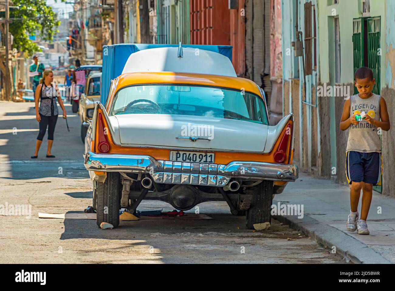 Yellow and white vintage car with an open hood parked on a street in Old Havana, Cuba Stock Photo