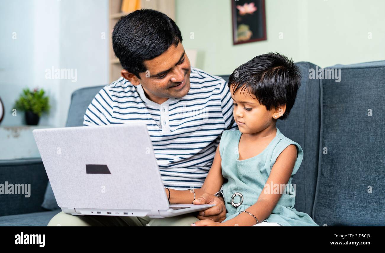 happy Father helping or teaching the daughter to use laptop at home - concept of home schooling, parental teaching and development Stock Photo