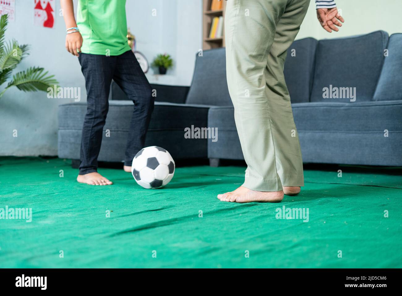 close up shot of father and son playing footballs at home by kicking - concept of leisure activity, family and practicing game Stock Photo