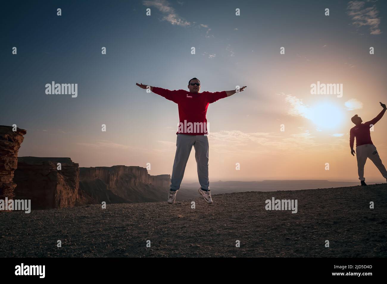 Happy Man jumping silhoutte poses with beautiful sunset background in Edge of the world Riyadh Saudi Arabia. Stock Photo