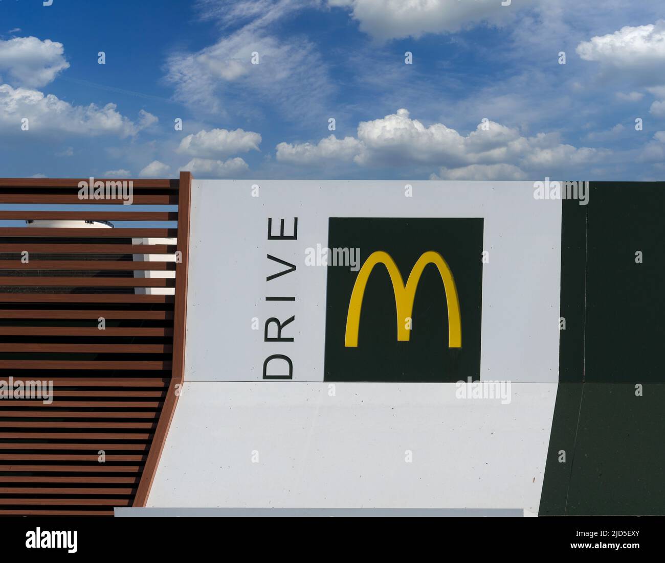 Savigliano, Italy - June 16, 2022: McDrive sign on  new McDonald's ristorante on blue sky cloudy. The McDonald's Corporation is world's largest chain Stock Photo