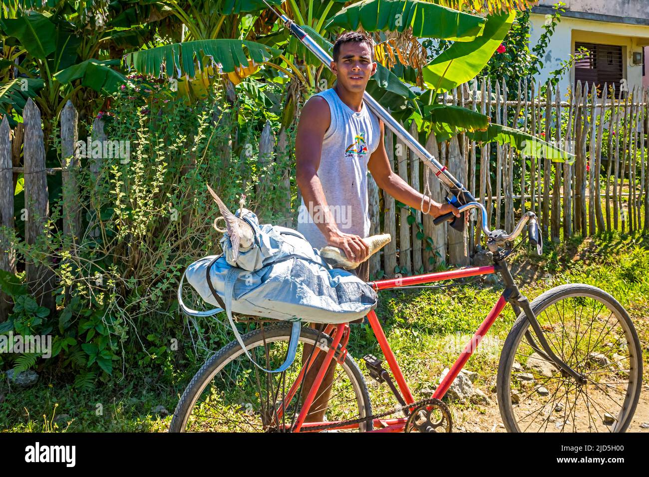 A young man coming from spearfishing and bringing his catch home by bicycle near Baracoa, Cuba Stock Photo