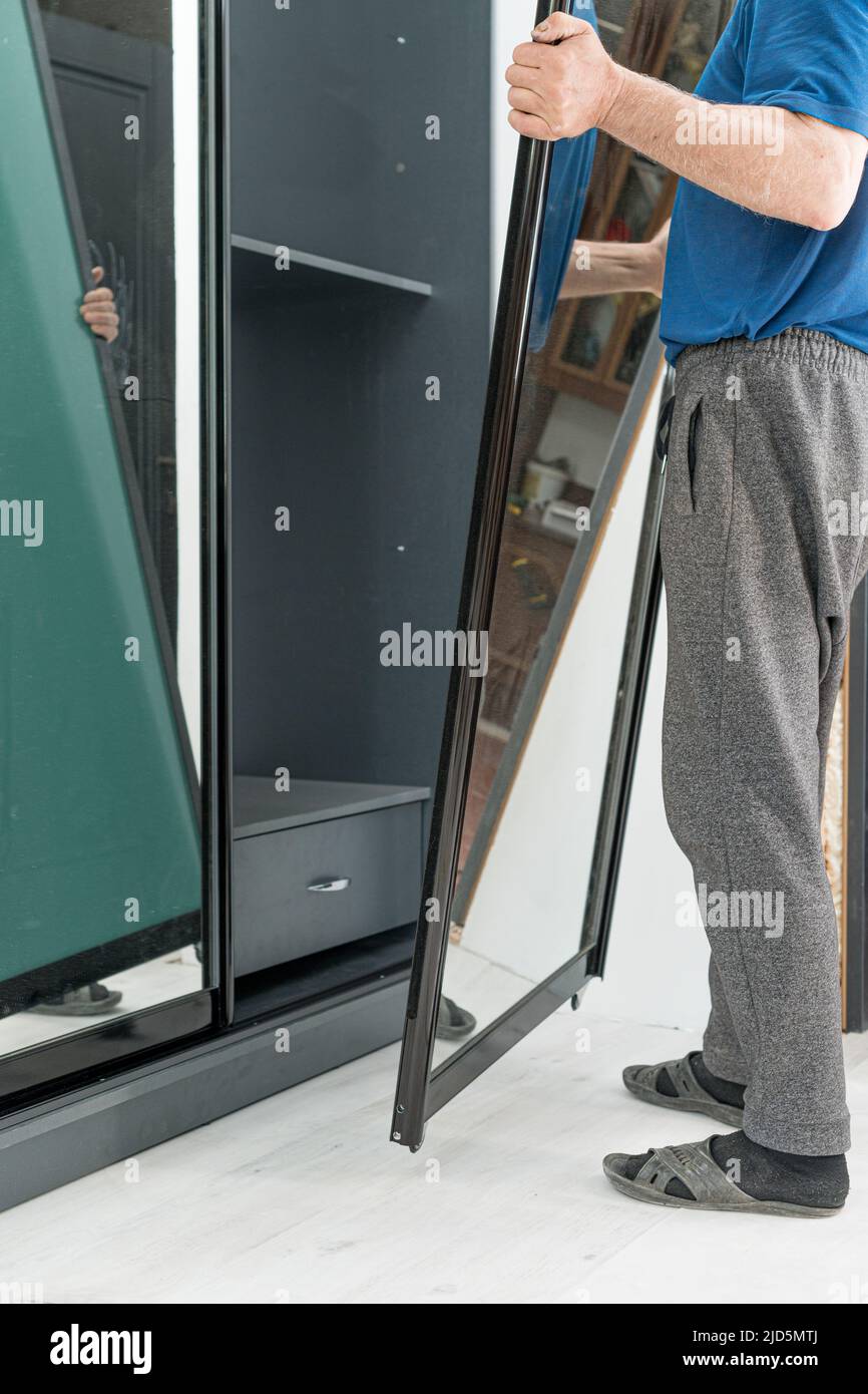 Assembly of a sliding wardrobe, a door of a wardrobe with a mirror, the master and the assistant